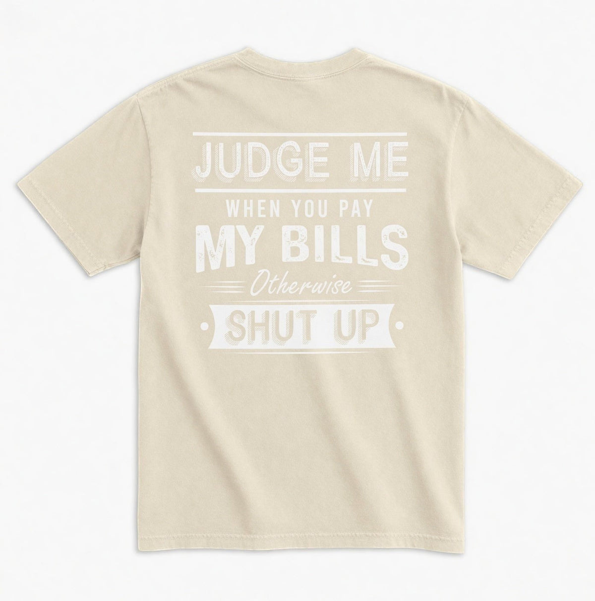 TrendyShift.Com beige unisex graphic tee with white distressed typography on the back reading Judge Me When You Pay My Bills. Otherwise SHUT UP.